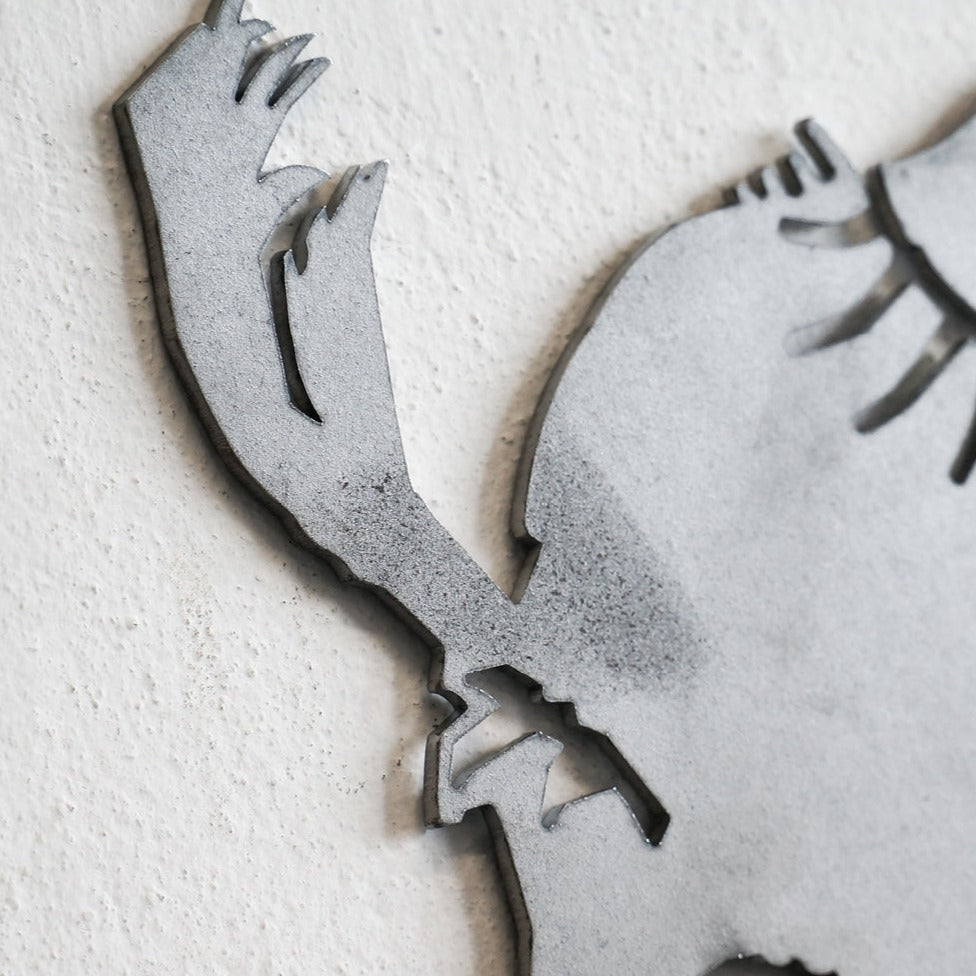 Close-up of Metalbird UK’s "Blue Tit - Seconds" wall art, crafted from premium gray corten steel, showing a stylized bird tail and body. Mounted on a textured white wall with slightly rough cut-out edges.