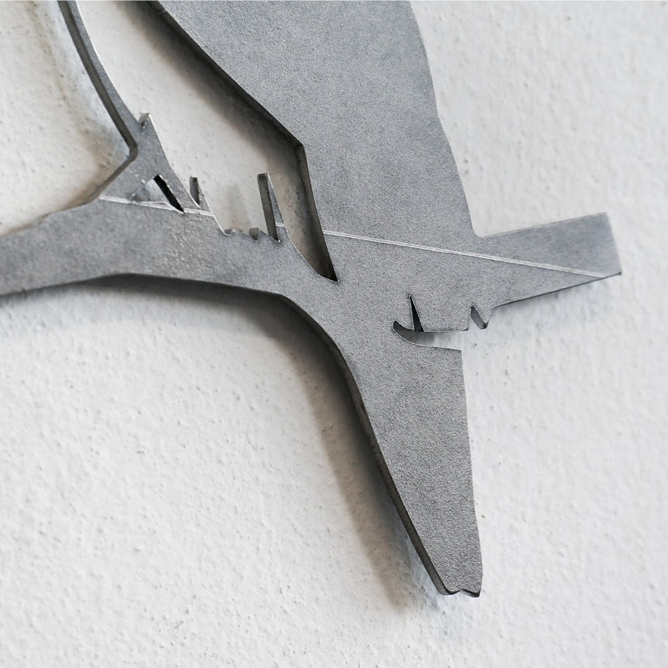 Close-up of the Blue Tit - Seconds by Metalbird UK, a minimalist corten steel wall art featuring a premium bird silhouette perched on a branch, mounted on a light-colored textured wall.