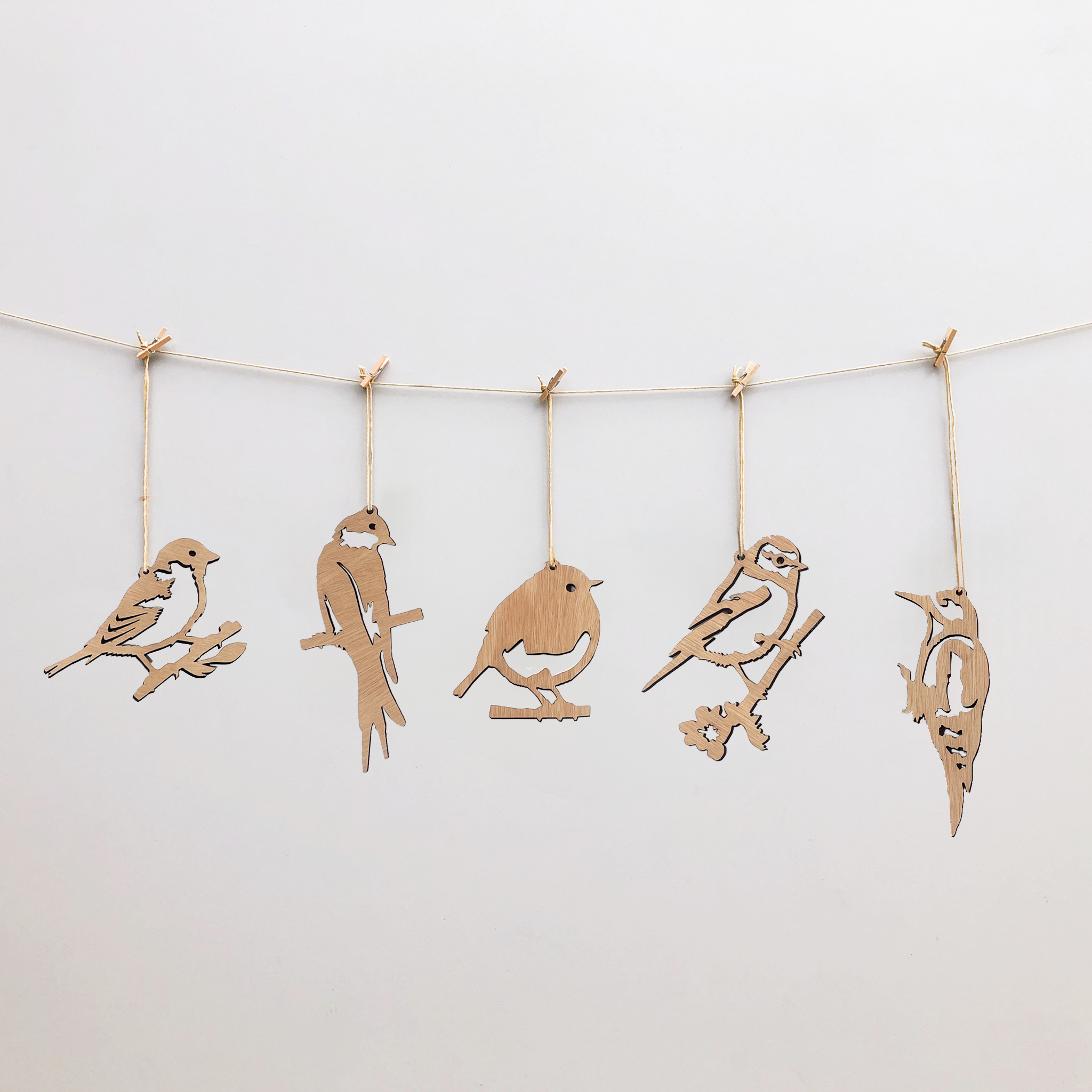 The Metalbird UK Wooden Hanging Decorations feature five bird-shaped silhouettes suspended by twine, creating charming yard art against any background.