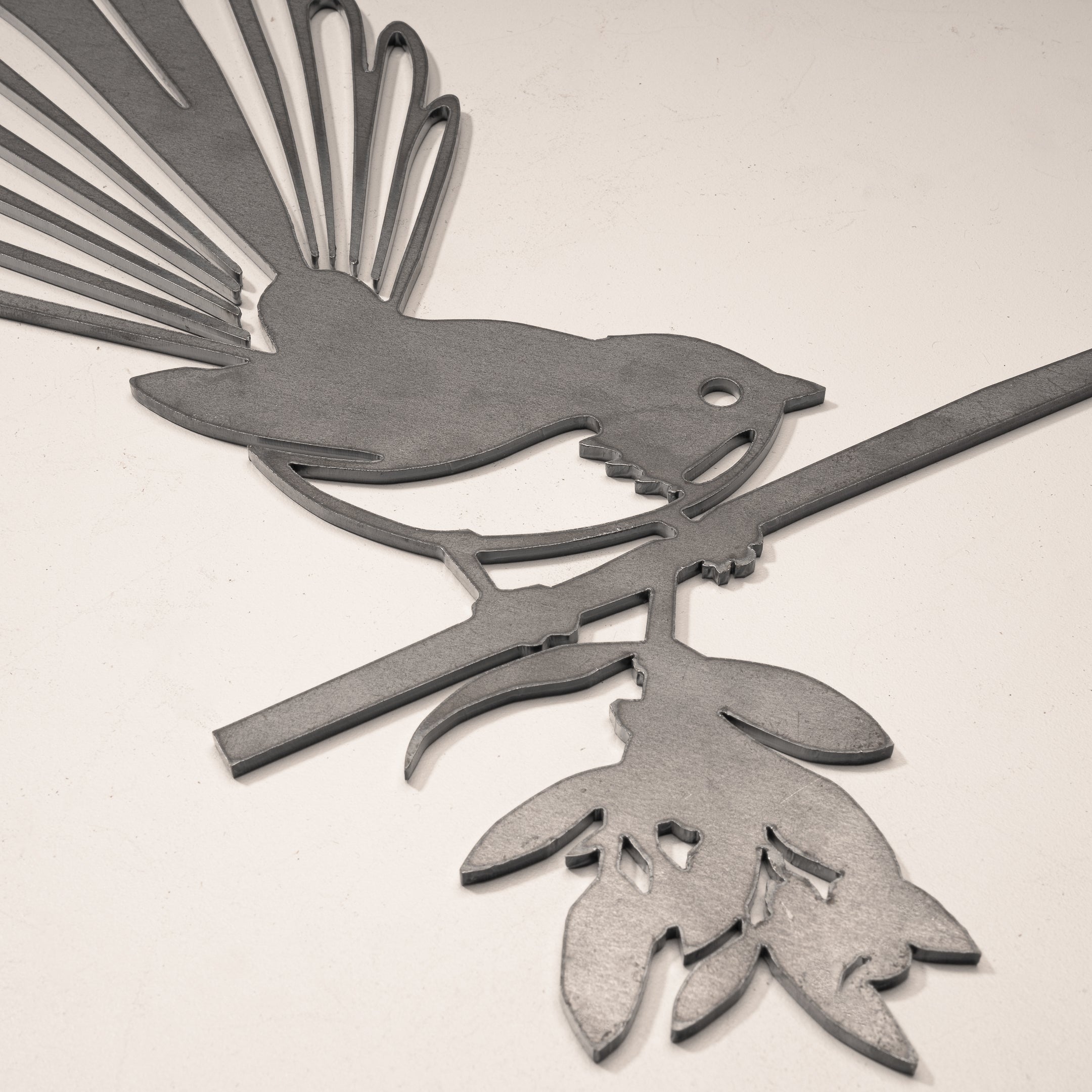 The Metalbird UK Fantail (Piwakawaka) is a corten steel cutout of a bird with a fanned tail on a leafy branch—an elegant garden art piece and perfect gift for nature lovers.