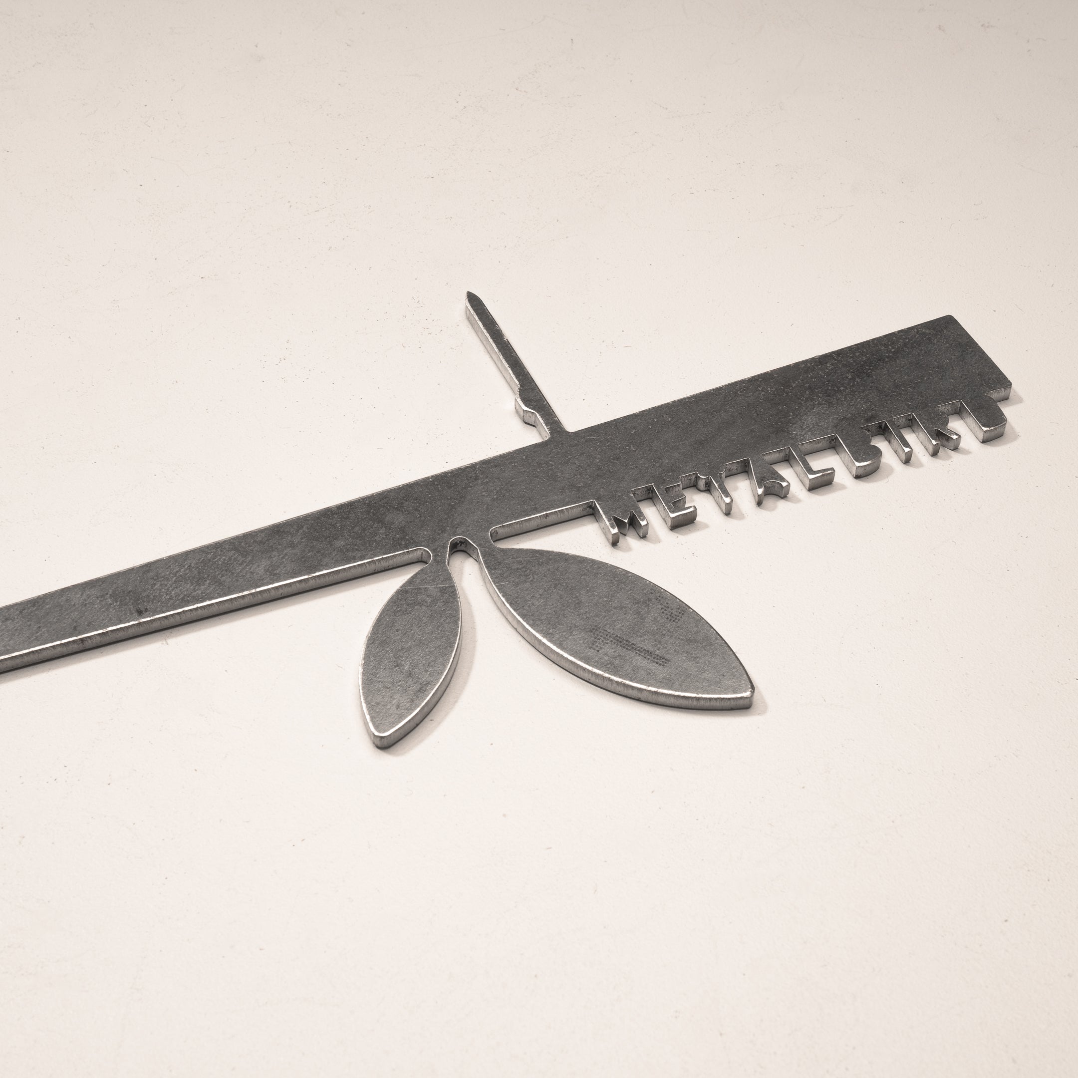 The Metalbird UK Stick Feeder is a metallic ruler-shaped object with a central stem and two oval forms, featuring small metal tabs along one edge—an eye-catching piece for your garden.