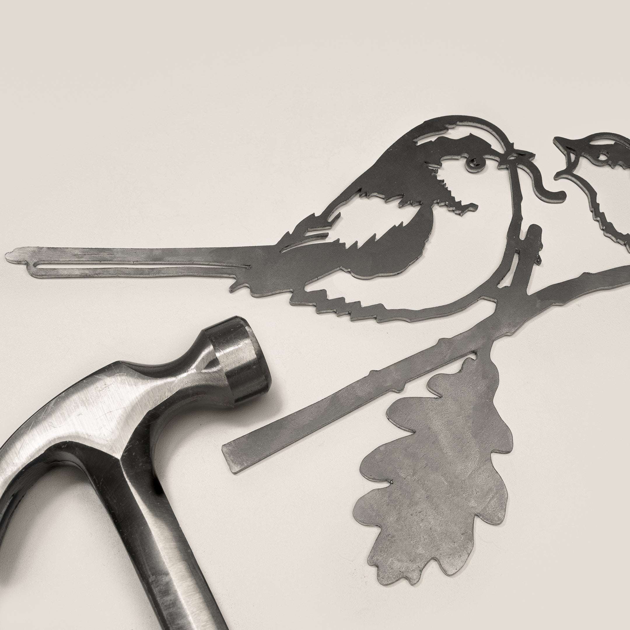 The Long-tailed Tit & Chick by Metalbird UK is a metal silhouette of two birds on branches, shown on a light surface with a silver hammer—perfect for adding charm to your garden art collection.