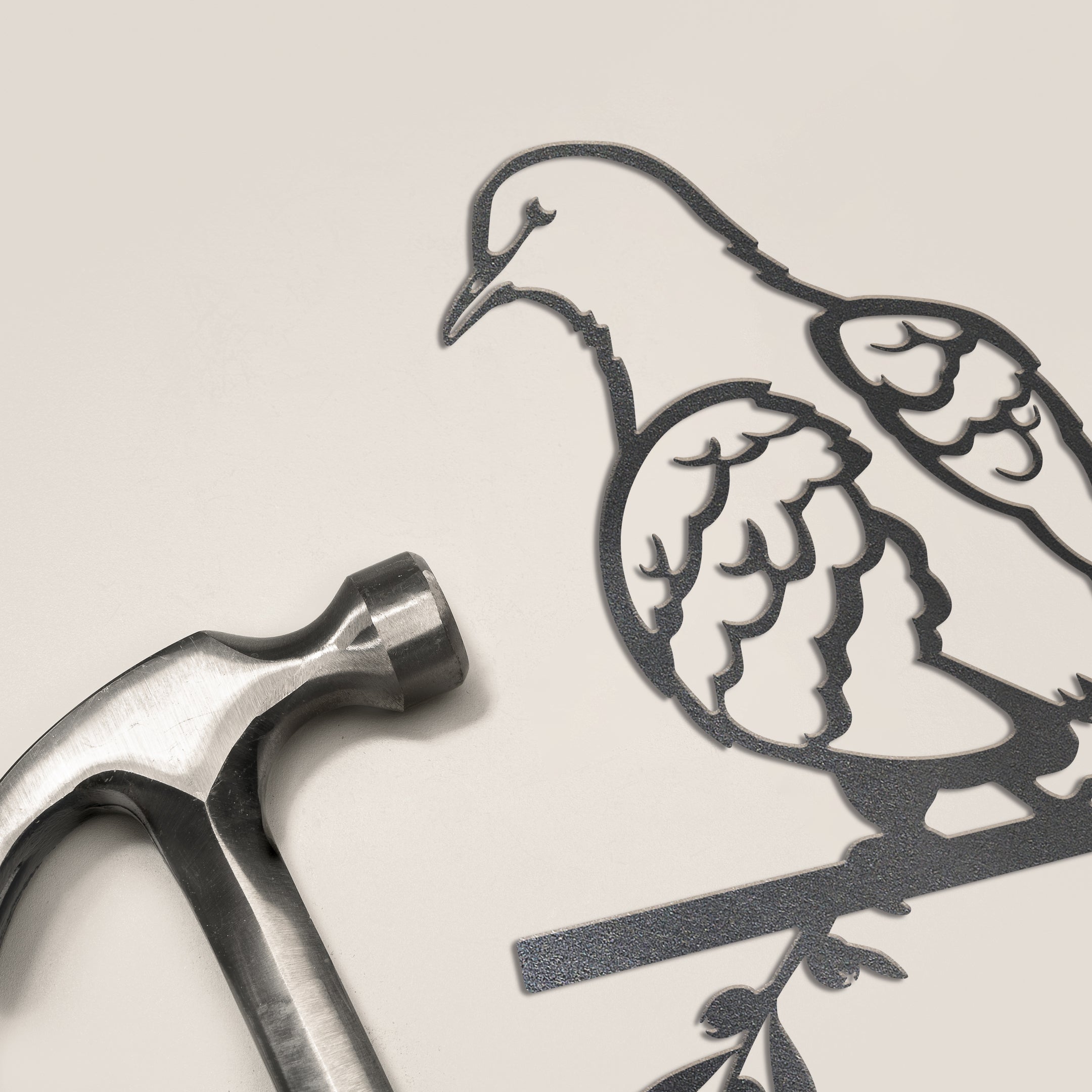 A metallic hammer sits beside the Turtle Dove silhouette by Metalbird UK, both displayed on a light surface, creating unique garden art inspiration.