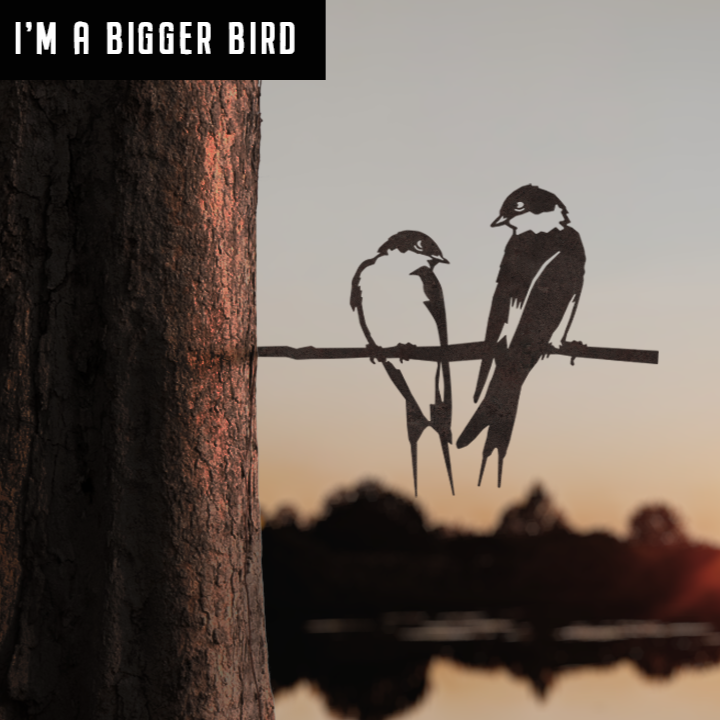 Two swallows in silhouette perch on a branch at sunset near water, one larger than the other. Bold white text reads IM A BIGGER BIRD—Pair of Swallows - Large by Metalbird UK, perfect as unique garden art or a whimsical gift.