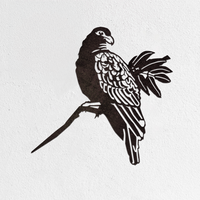 The Manumea - Seconds by Metalbird UK is a premium black corten steel parrot silhouette perched on a branch, mounted on a white textured wall.