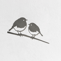 Metalbird UK’s Metalbird Seconds - Robin Pair features two birds on a branch, mounted on a white textured wall—ideal as discounted garden decor or unique metal bird ornaments for your home.