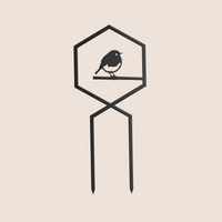 The Robin Plant Trellis by Metalbird UK is a black metal garden stake with a hexagonal frame and bird silhouette perched on a branch, creating charming garden art set against a light beige background.