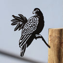 The Manumea by Metalbird UK - CC is a premium black corten steel bird silhouette attached to a wooden post, casting a striking shadow against a light gray background—ideal as unique yard art.