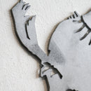 Close-up of Metalbird UK’s "Blue Tit - Seconds" wall art, crafted from premium gray corten steel, showing a stylized bird tail and body. Mounted on a textured white wall with slightly rough cut-out edges.