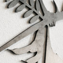 Close-up of the Metalbird Seconds - Lesser Florican wall decoration by Metalbird UK, shaped like a tree branch with leaves. The weathered metal finish adds charm to this elegant bird garden sculpture, mounted on a white textured wall.