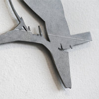 Close-up of the Blue Tit - Seconds by Metalbird UK, a minimalist corten steel wall art featuring a premium bird silhouette perched on a branch, mounted on a light-colored textured wall.
