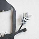A close-up shows the Metalbird Seconds - Fantail by Metalbird UK, a black metal bird silhouette with minor imperfections on a textured white wall—ideal for fans of unique discount garden art.