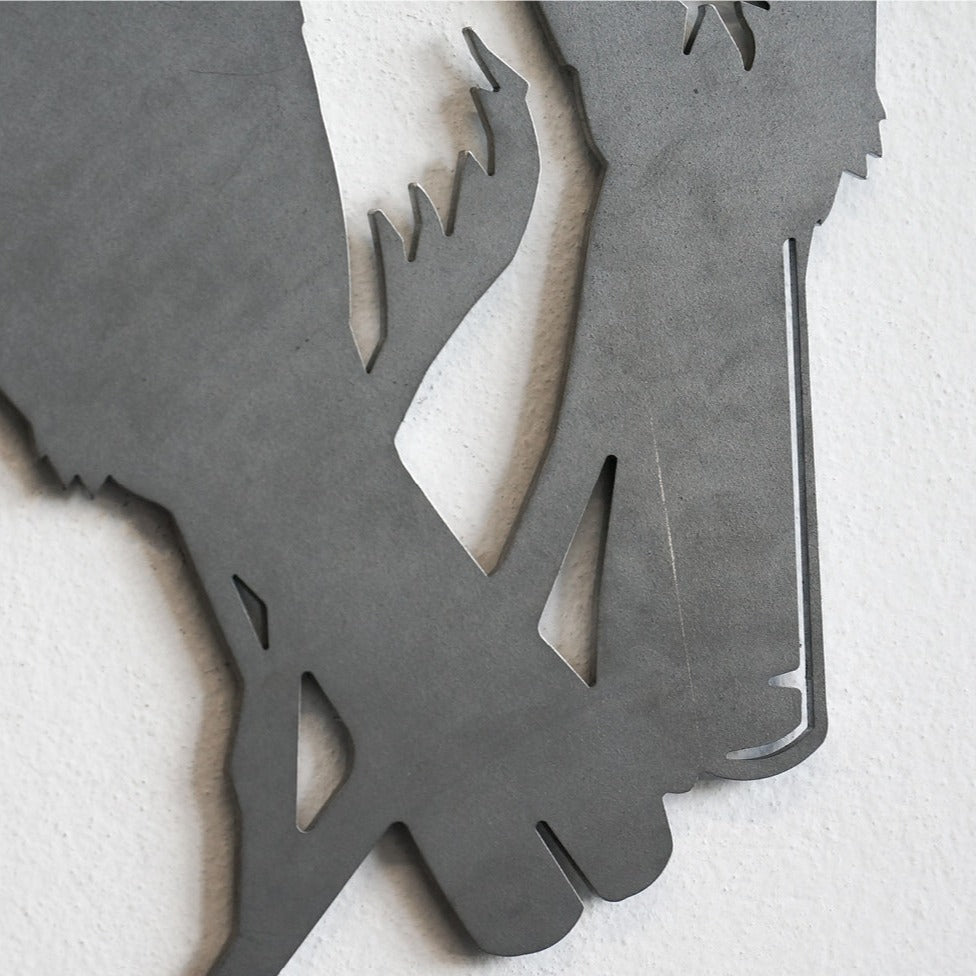 Close-up of the Metalbird Seconds - Lesser Florican by Metalbird UK, a metal wall art piece with two stylized bird legs crossing, mounted on a white textured wall.