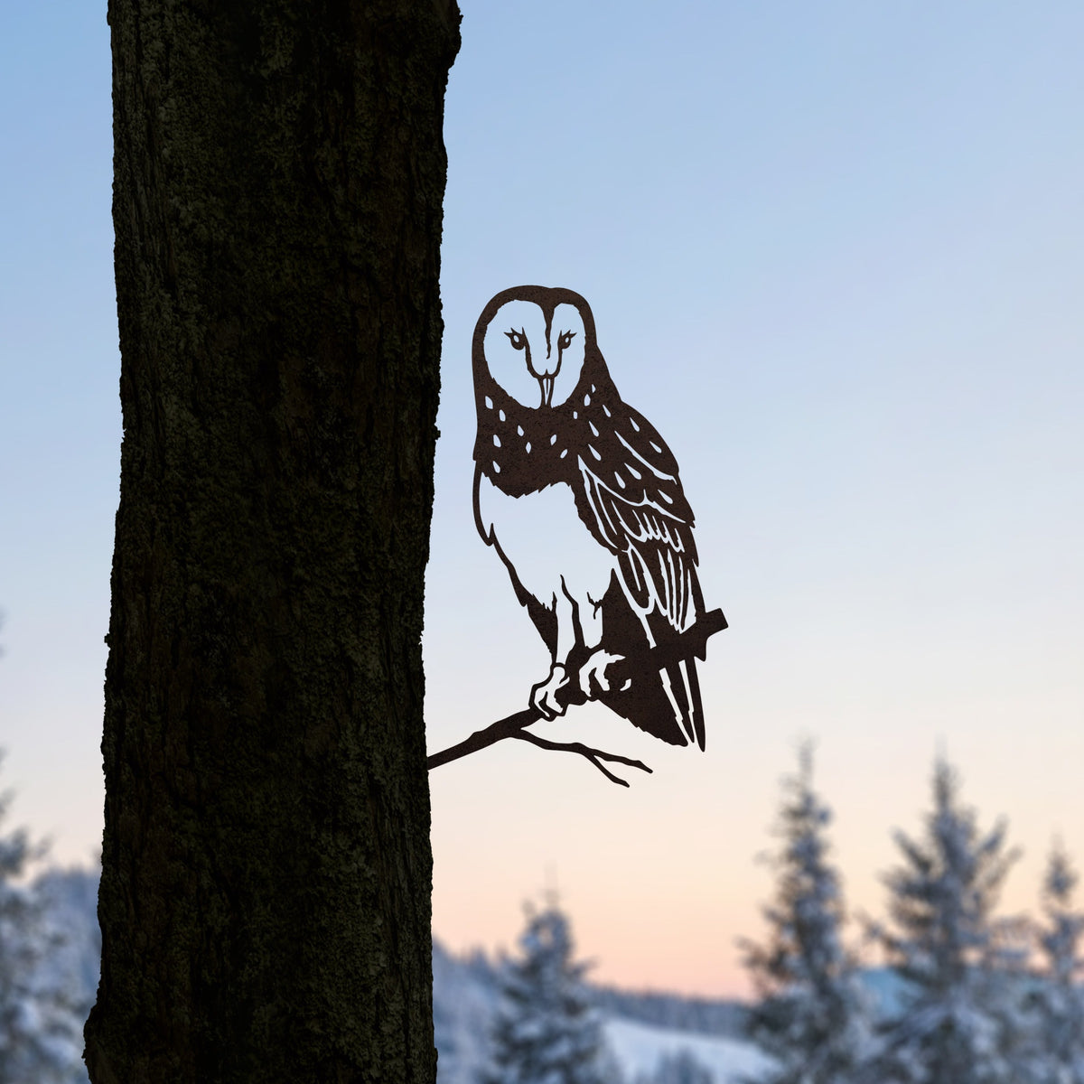 Barn Owl steel silhouette mounted on a tree trunk against a winter sunset.