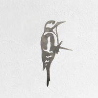 The Metalbird UK "Great Spotted Woodpecker - Seconds" is a premium metal silhouette with clean lines, depicting the bird in profile and upright, mounted on a textured white wall.