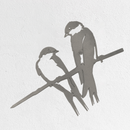 The Metalbird UK "Pair of Swallows - Seconds" is a minimalist metal wall art piece featuring two birds on a branch, elegantly displayed against a white textured wall—an ideal gift.