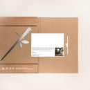 A brown cardboard folder from Metalbird UK, featuring a knife and olive branch cutout design, partially opened to reveal a white card titled "Stick Feeder" with text and a black-and-white photo of someone at a table.