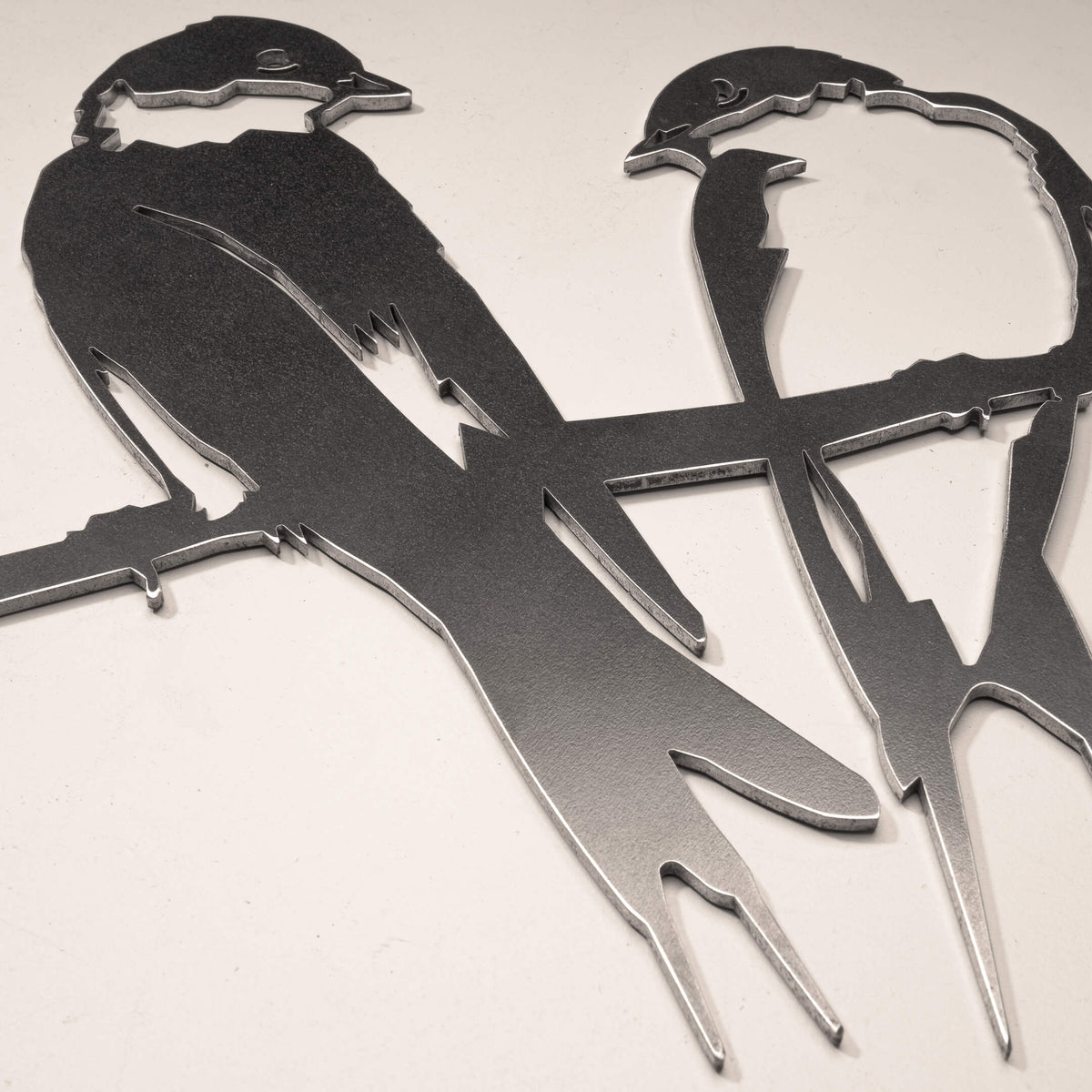 Close-up of the cut-steel swallows, showing feather detail and long tails.
