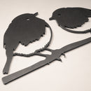 The Robin Pair by Metalbird UK features a black metal silhouette of two birds perched on a branch. With simple cutouts and small holes near the heads, it makes a charming gift or decorative accent for any space.