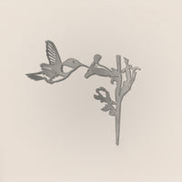 The Hummingbird by Metalbird UK features a grayscale silhouette of a hovering hummingbird beside a flower, set against a light background—ideal as unique garden art or a thoughtful gift.