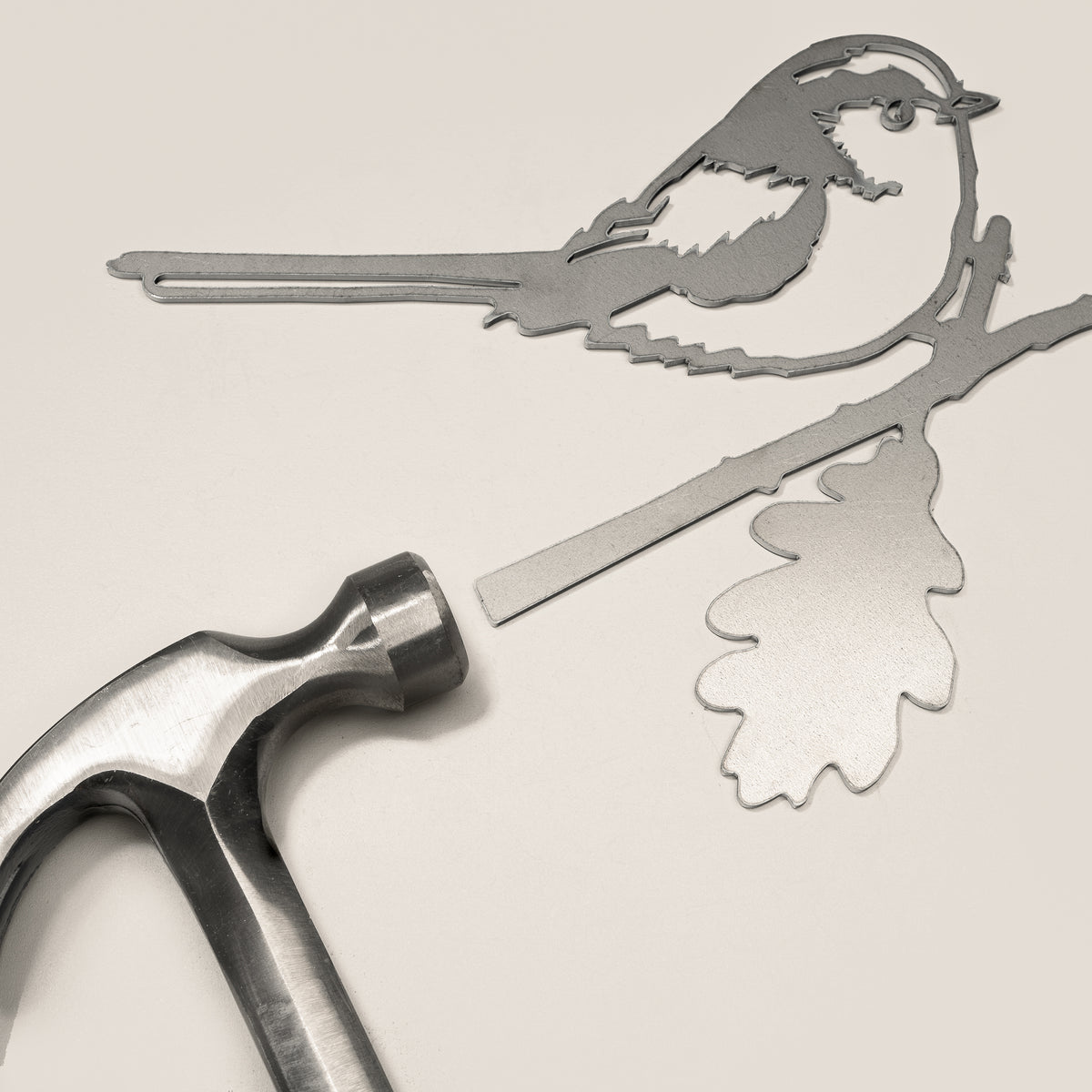 Long-tailed Tit steel silhouette and mounting spike beside a hammer.