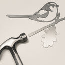 The Metalbird UK Long-tailed Tit features a flat metal bird silhouette perched on an oak branch, with a hammer included for easy installation—perfect as eye-catching yard art or a unique gift.