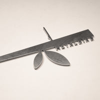 The Metalbird UK Stick Feeder is a metallic ruler-shaped object with a central stem and two oval forms, featuring small metal tabs along one edge—an eye-catching piece for your garden.
