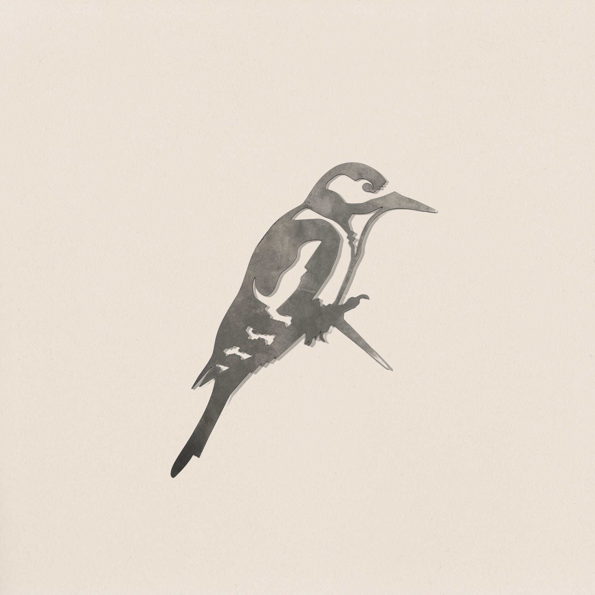 A minimalist, monochrome Great Spotted Woodpecker by Metalbird UK, shown perched in profile against a light background—ideal garden art or gift, inspired by the sleek lines of corten steel sculptures.