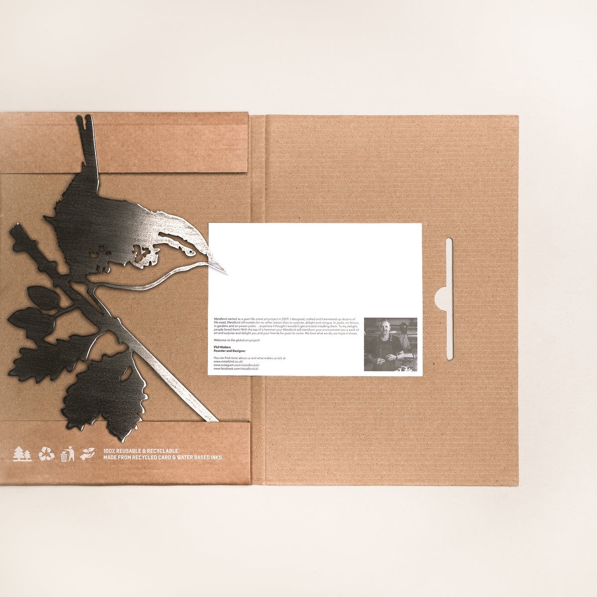 Wren steel silhouette laid across open cardboard packaging with an information card.