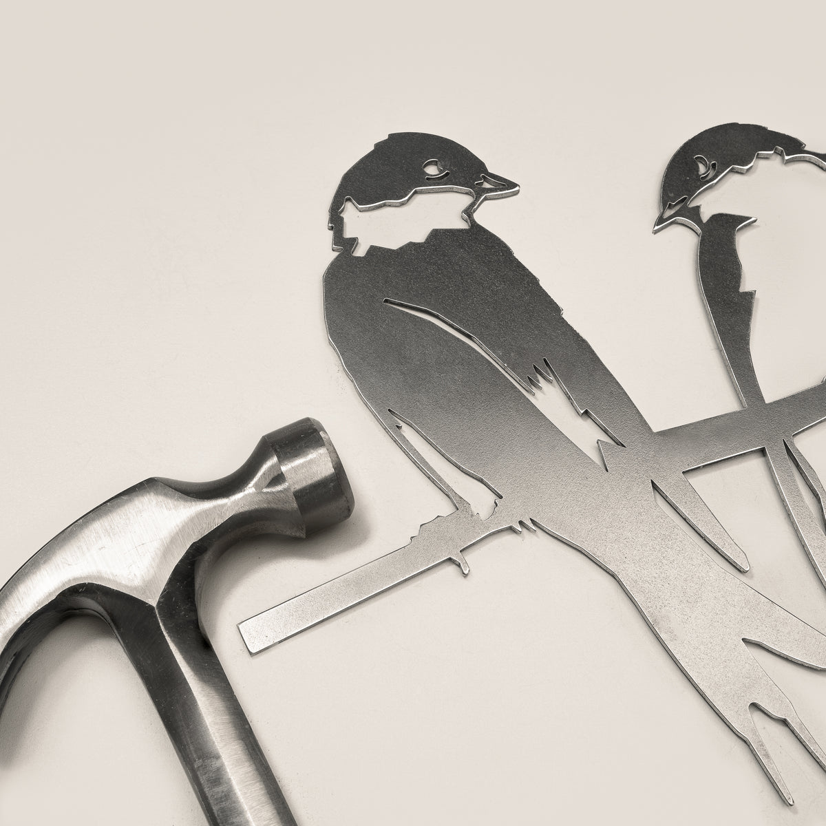 Pair of Swallows silhouette and integrated mounting spike beside a claw hammer.