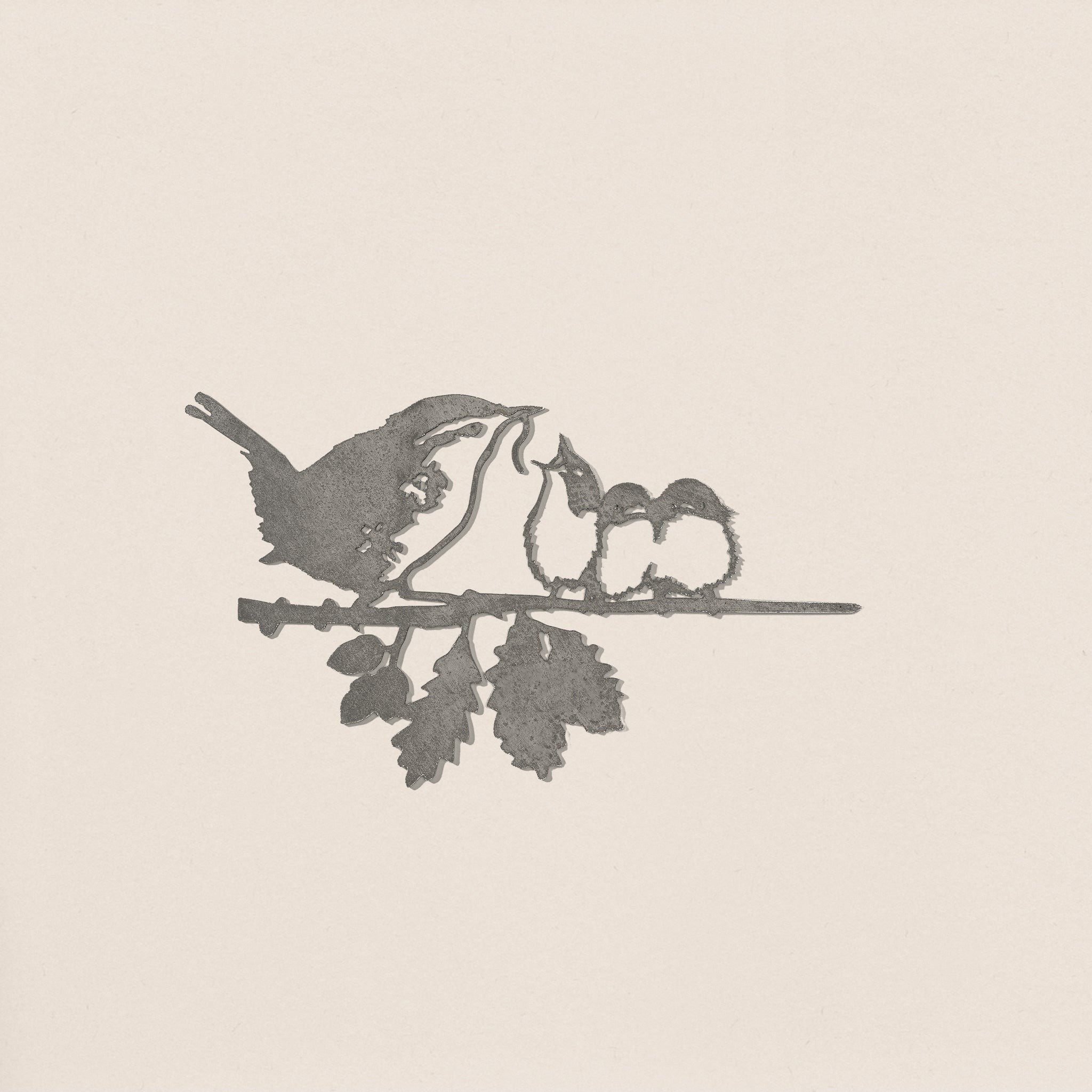 The Metalbird UK "Wren and Chicks" is a grayscale silhouette of a bird feeding two chicks on a leafy branch, set against a plain background—a heartfelt gift for any occasion.