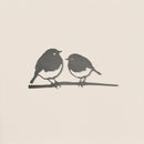 The Robin Pair by Metalbird UK features a simple black and white illustration of two small birds facing each other on a thin branch, evoking garden art, set against a plain light background.