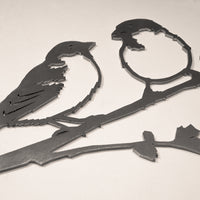 The "Pair of Sparrows" by Metalbird UK is metal wall art made from corten steel, showing two stylized birds on a branch—one detailed and one silhouette—against a plain light background.