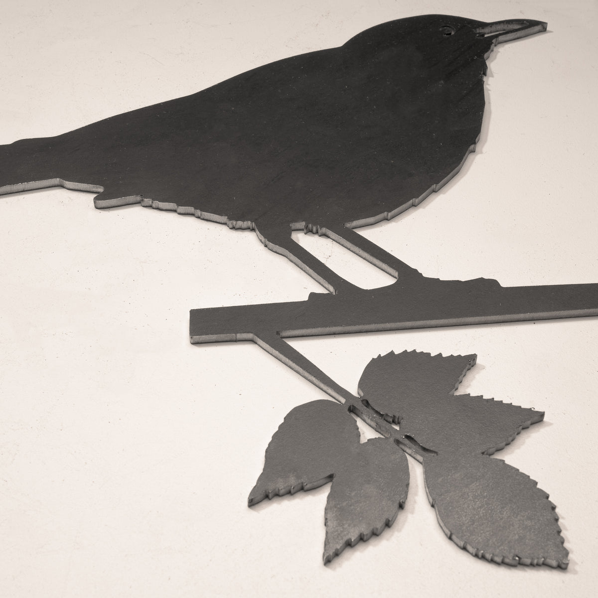 Close-up of the Blackbird’s cut-steel profile, branch and leaves.