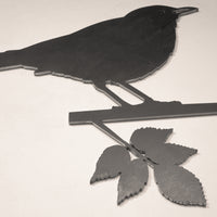 The Blackbird by Metalbird UK is a corten steel silhouette of a bird on a leafy branch, designed to mount on any light wall—a striking yard art piece for your outdoor space.