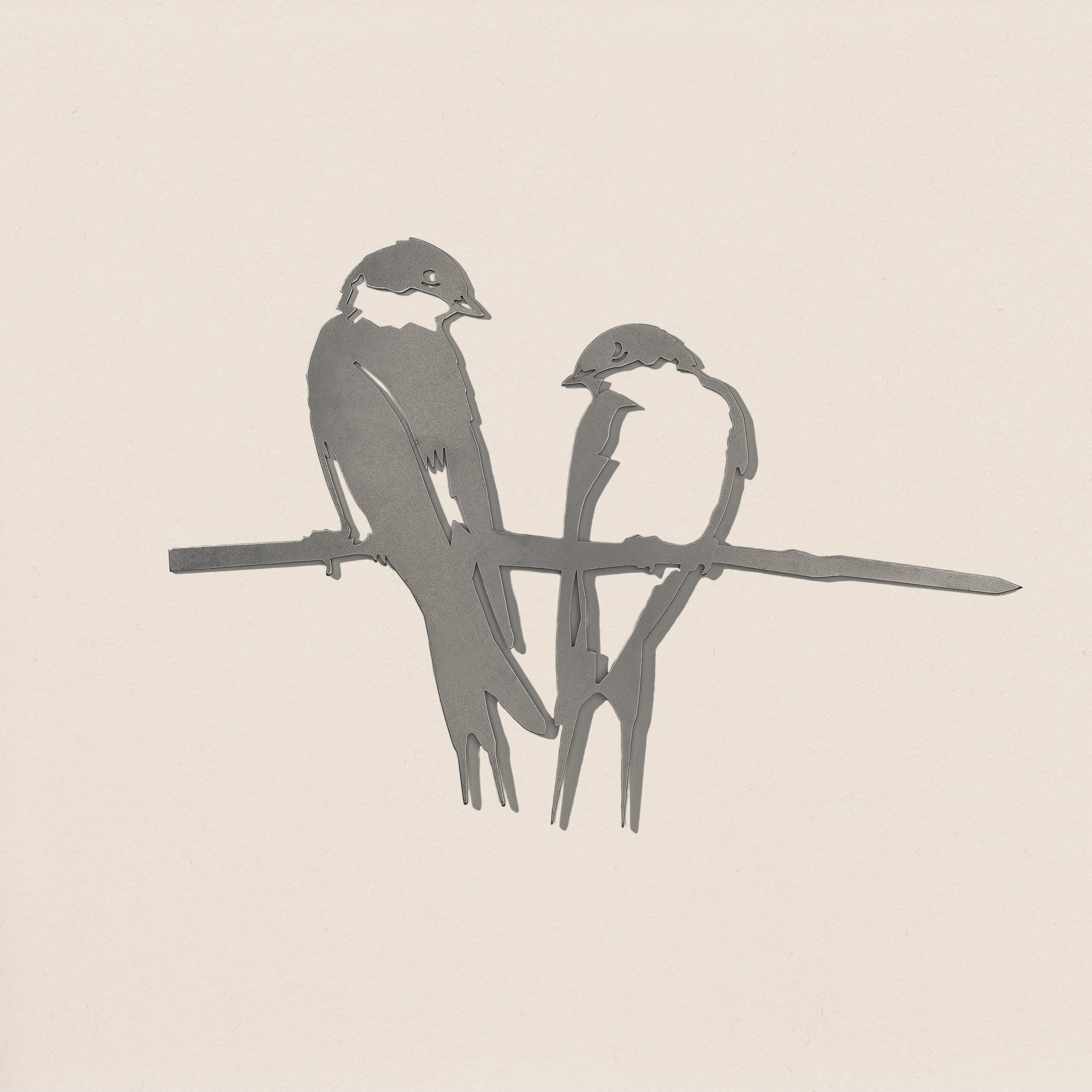 The Pair of Swallows by Metalbird UK features a minimalist design of two birds on a branch in simple gray lines, set against a light background—an elegant choice for yard art or as a thoughtful gift.