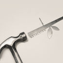 The Metalbird UK Stick Feeder faces a metal ruler with leaf cutouts and "EVOLUTION" text, creating unique metal garden art—an ideal gift for nature and design lovers.