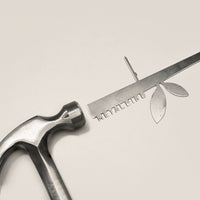 The Metalbird UK Stick Feeder faces a metal ruler with leaf cutouts and "EVOLUTION" text, creating unique metal garden art—an ideal gift for nature and design lovers.