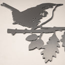 The Metalbird UK Wren is a minimalist, flat corten steel silhouette showing a wren perched on a leafy branch in profile, displayed on a light-colored surface.