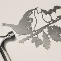 The Wren and Chicks by Metalbird UK features a corten steel cutout of a bird feeding its three chicks on a leafy branch—perfect as unique garden art or a thoughtful gift.