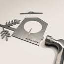 A flat metal Bird Feeder by Metalbird UK, decorated with a branch and hammer on a plain white surface—ideal as unique yard art.