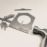 A flat metal Bird Feeder by Metalbird UK, decorated with a branch and hammer on a plain white surface—ideal as unique yard art.