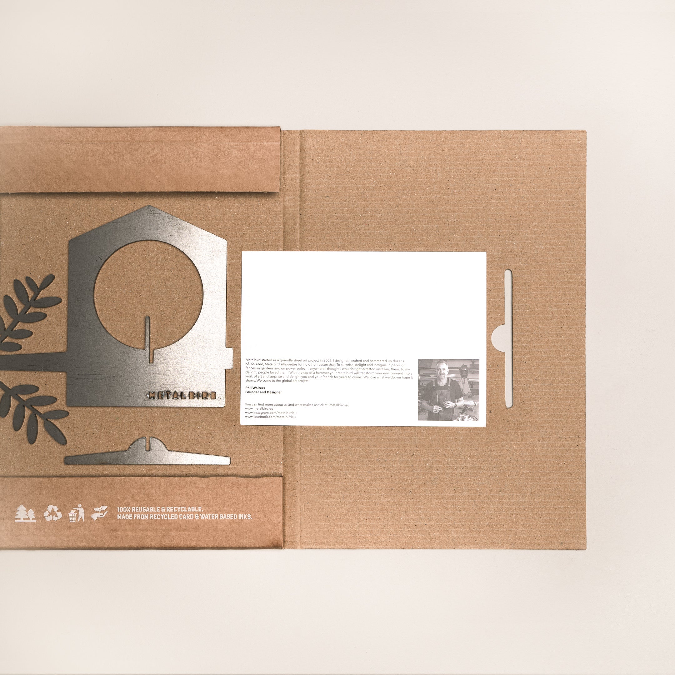 An open cardboard package from Metalbird UK holds a flat metal Bird Feeder kit, a white instruction card, and leaf cutouts on a light background—the perfect eco-friendly gift for garden art lovers.