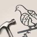 A metallic hammer sits beside the Turtle Dove silhouette by Metalbird UK, both displayed on a light surface, creating unique garden art inspiration.