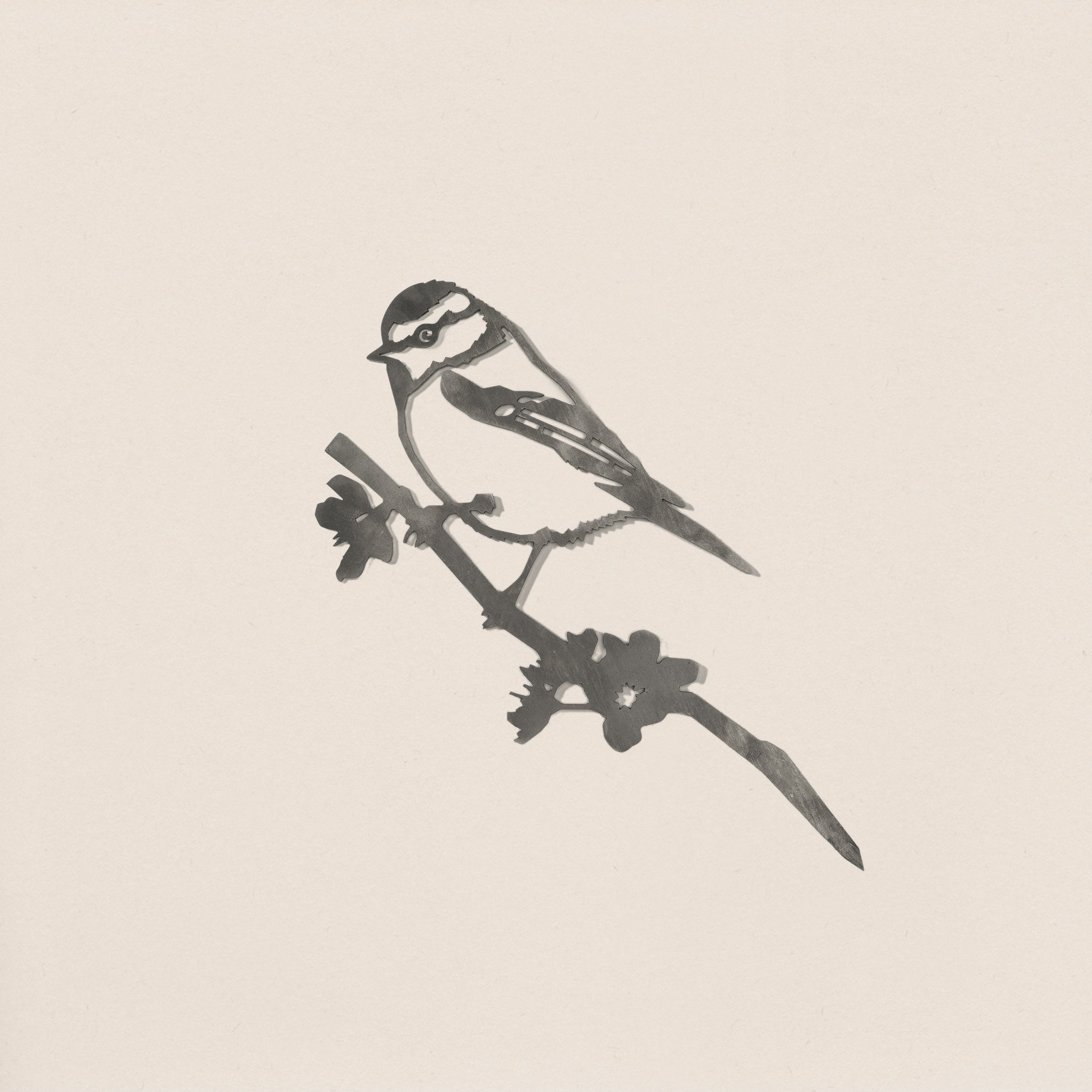 Minimalist ink illustration of a Blue Tit silhouette perched on a leafy branch by Metalbird UK, perfect as garden art or a thoughtful gift, set against a plain, light background.