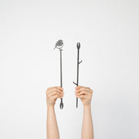 Two hands hold up Metalbird UK's Robin Plant Stake - 70cm against a white background: one features a bird silhouette, the other has branch details—an ideal unique gift or creative accent for your yard art collection.