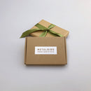 Two brown boxes on a light surface—one with a green ribbon, the other plain and labeled "METALBIRD PROUDLY MADE IN THE UK"—suggest the Baby Bird Bundle by Metalbird UK, unique garden art crafted from premium corten steel.