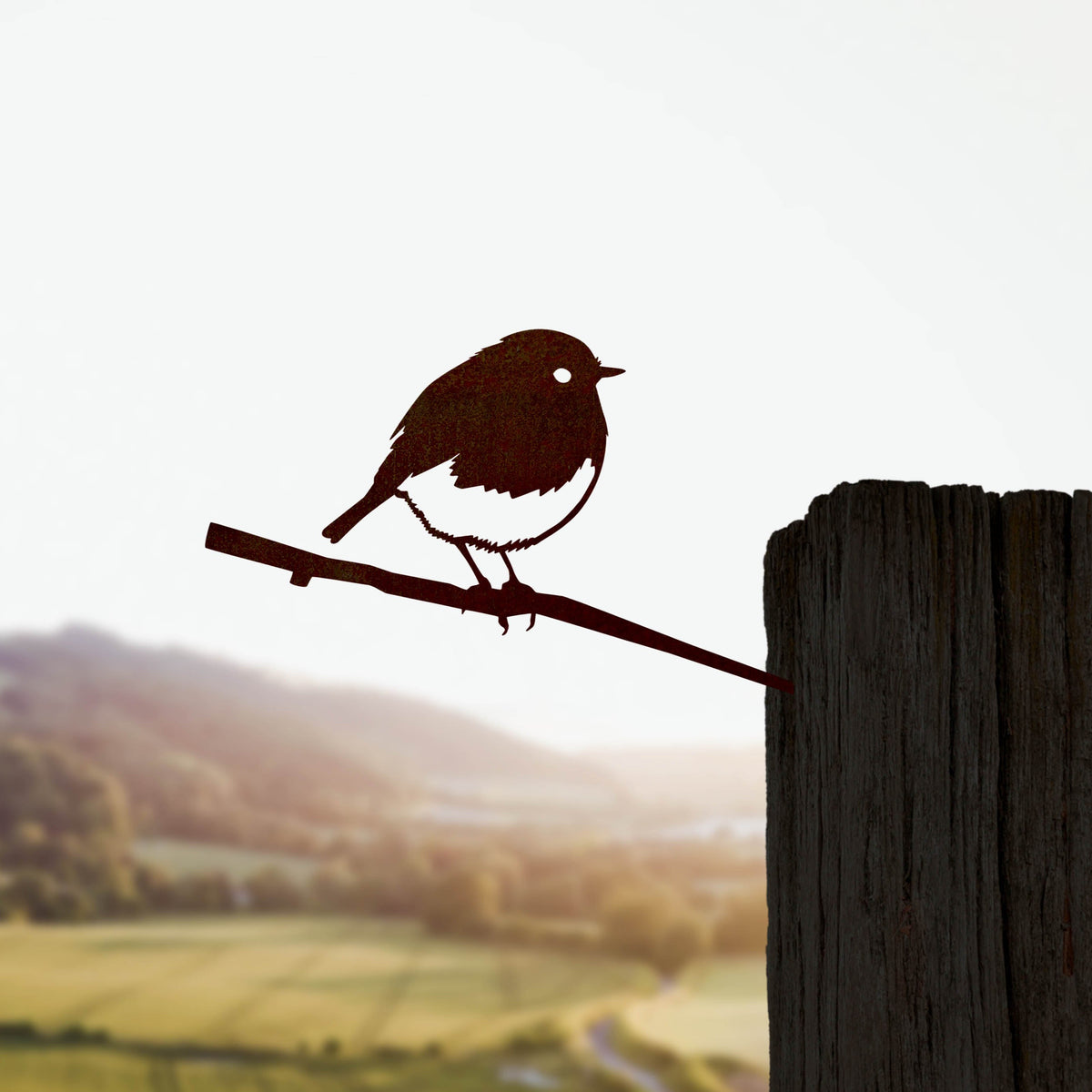 Metalbird Robin silhouette installed on a wooden fence post overlooking fields.